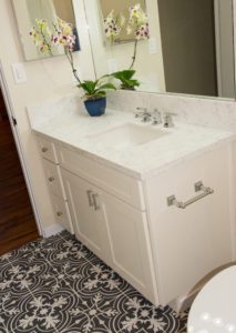 A bathroom with white cabinets and black tile floor.