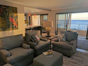 A living room with grey furniture and a view of the ocean.