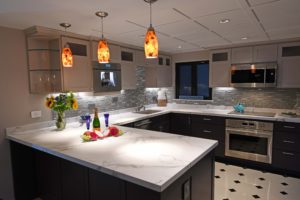 A kitchen with white counters and black cabinets.