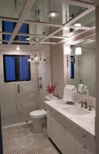 A bathroom with marble walls and floors, white fixtures.