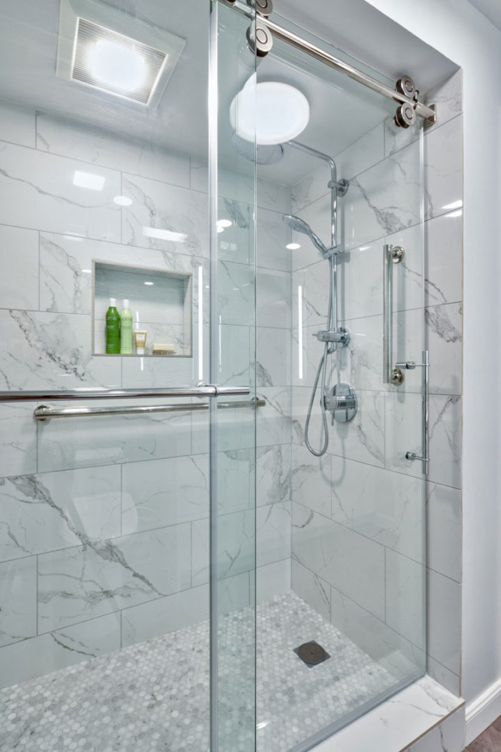 A bathroom with marble walls and white tile.