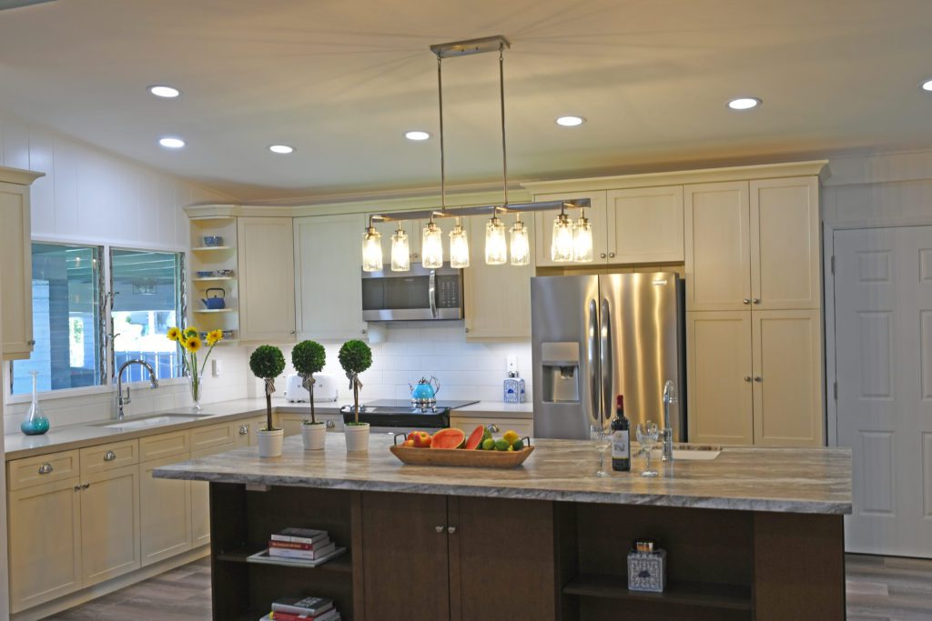 A kitchen with a large island and lights on.