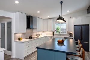 A kitchen with white cabinets and black counter tops.