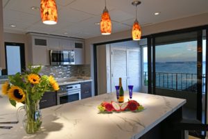 A kitchen with a large island and wine bottles on the counter.