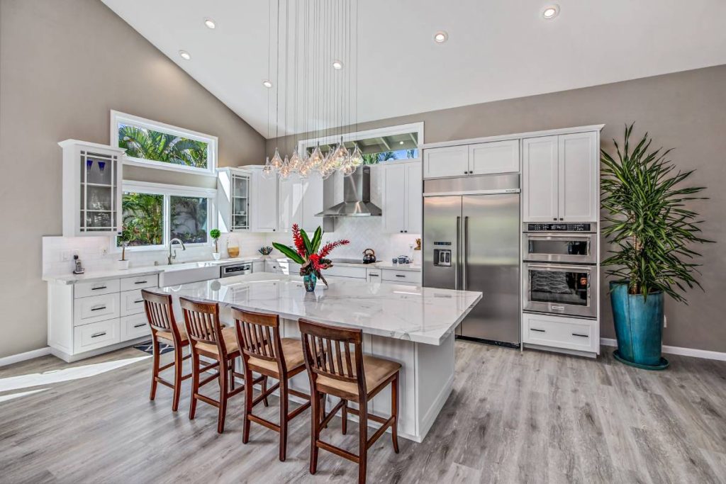 A large kitchen with white cabinets and wooden chairs.