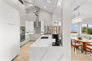 A kitchen with white cabinets and wooden floors.