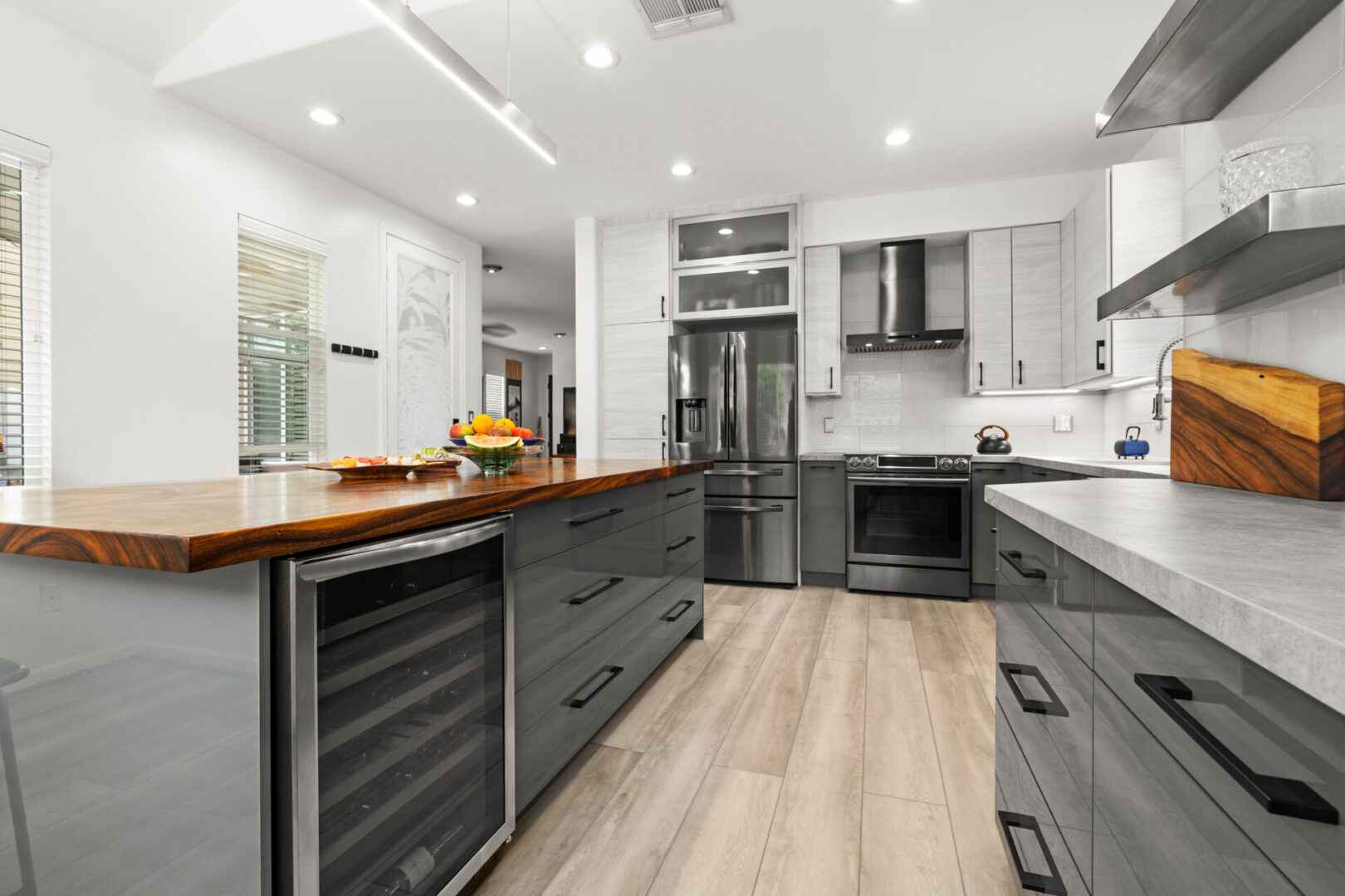 A kitchen with grey cabinets and wood floors.