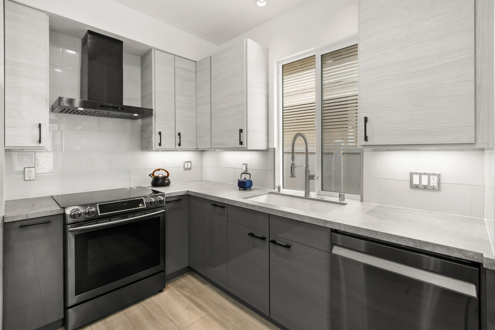 A kitchen with grey cabinets and black appliances.