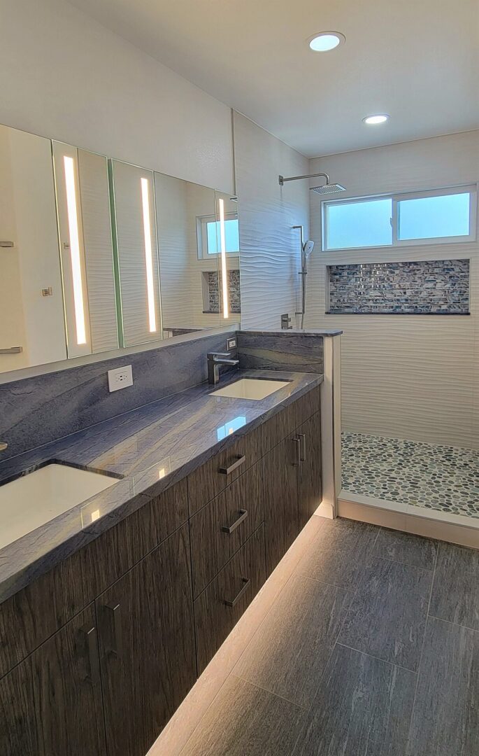 A bathroom with two sinks and a walk in shower.